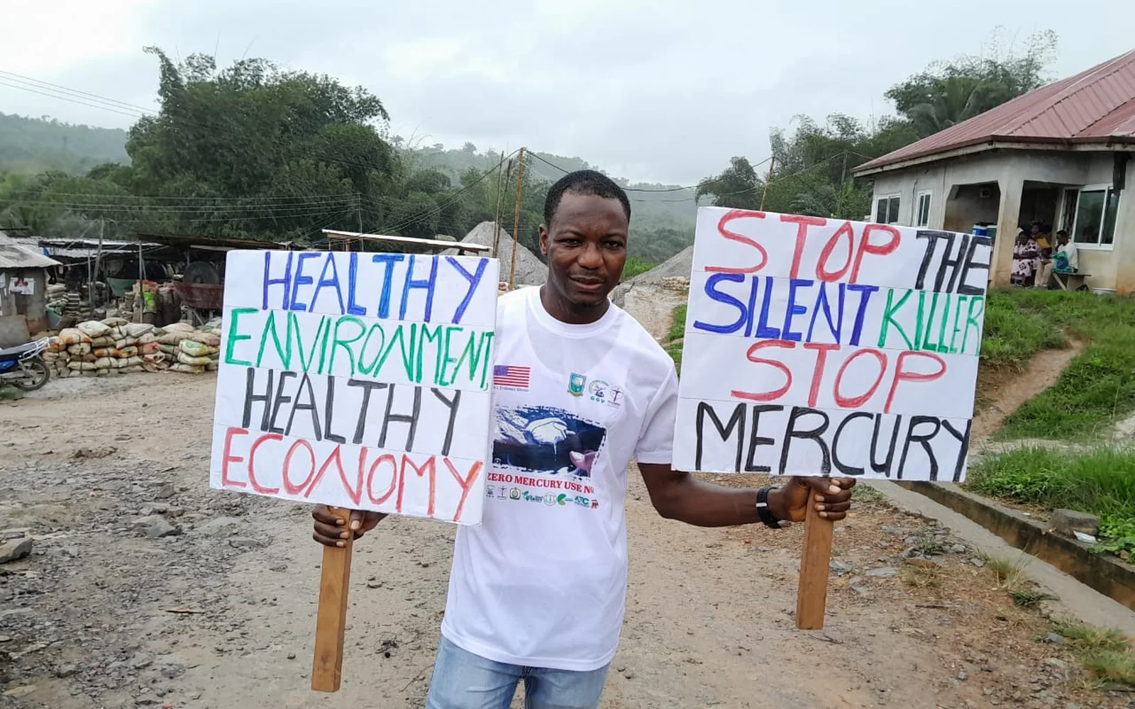 An advocate holding signs calling for healthy environments and an end to mercury use